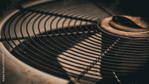 extreme close-up of a fan grille with moving blades below on an outdoor air conditioning unit. hvac or heat wave background. energy business or industry design element