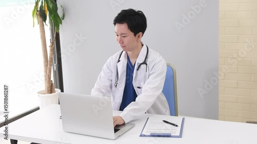 ノートPCで作業をする医療従事者の男性