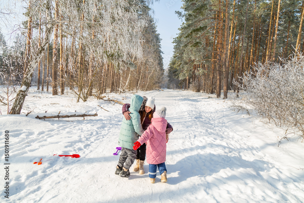 Naklejka premium Mother with children walking in nature in the winter forest
