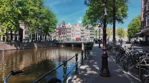 Explore Amsterdams charming streets in this captivating video showcasing a picturesque canal lined with bicycles, blending urban life and nature