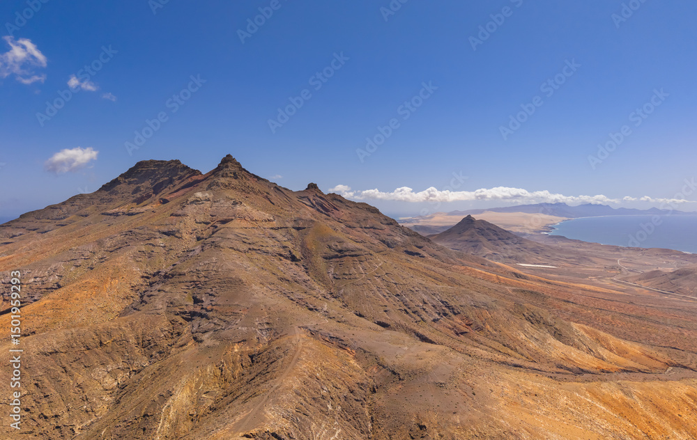 Naklejka premium Dramatic aerial panoramic image of Montana Cardon, the Jandia peninsular and the volcanic mountain landscape of Fuerteventura Canary Islands Spain