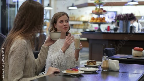 Wallpaper Mural Two girls enjoying lively conversation over coffee in a cozy café Torontodigital.ca