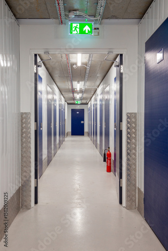 Long hallway within a modern, well-lit self-storage facility with blue doors