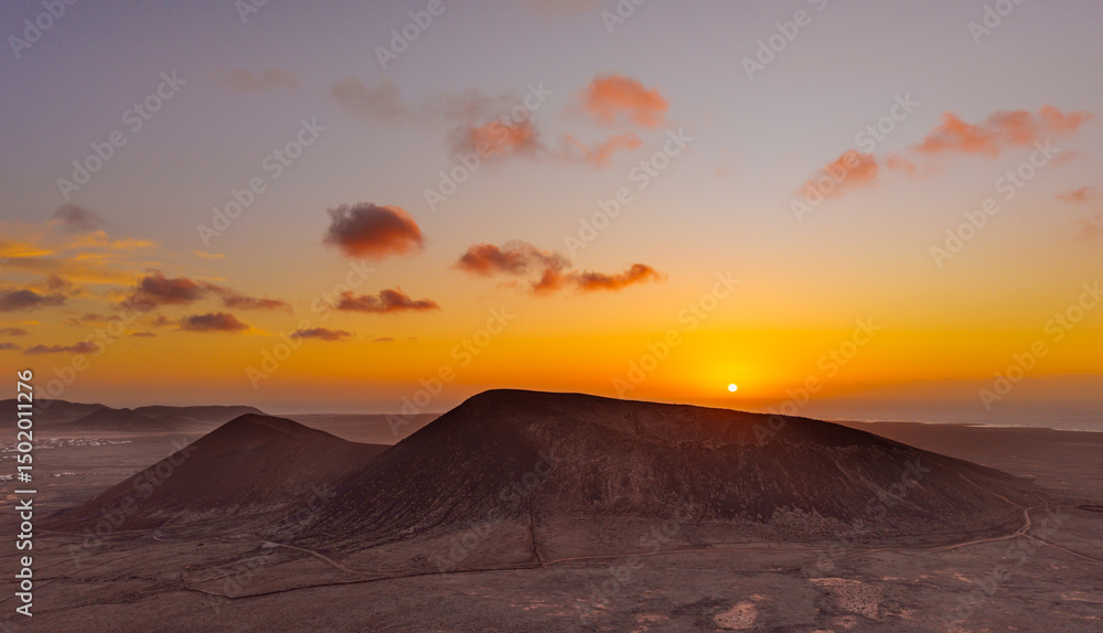 Naklejka premium Spectacular sun set image over Volcan Calderon Hondo volcanic crater silhouetted against the setting sun and skyscape near Corralejo, Fuerteventura, Canary Islands, Spain