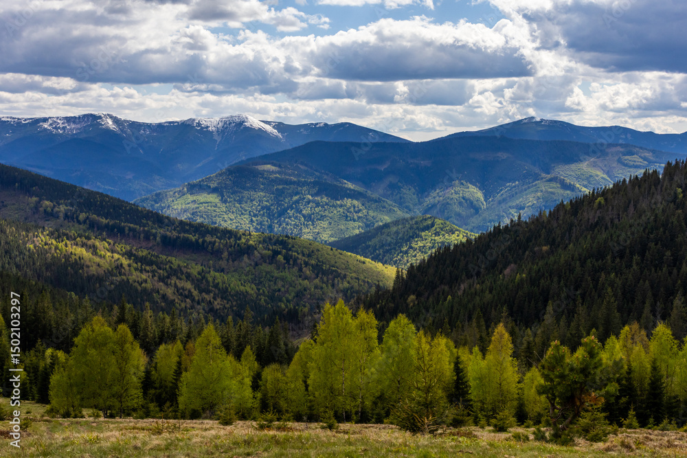 Expansive panoramic view of the Carpathian mountains, with snowy peaks and deep green valleys illuminated by dramatic spring light Expansive panoramic view of the Carpathian mountains, with snowy peaks and deep green valleys illuminated by dramatic spring light