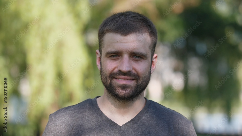 A man with a short beard stands confidently in a park, enjoying a bright sunny afternoon while surrounded by lush greenery, radiating positivity and warmth. A man with a short beard stands confidently in a park, enjoying a bright sunny afternoon while surrounded by lush greenery, radiating positivity and warmth.