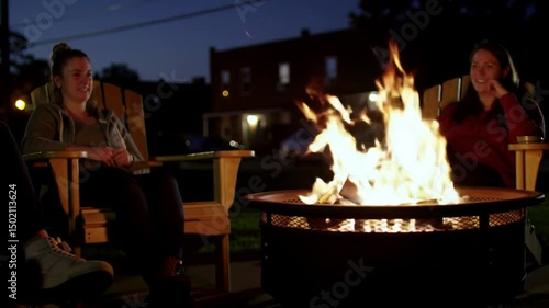 Friends Gather Around A Backyard Fire Pit On A Cool Summer Evening