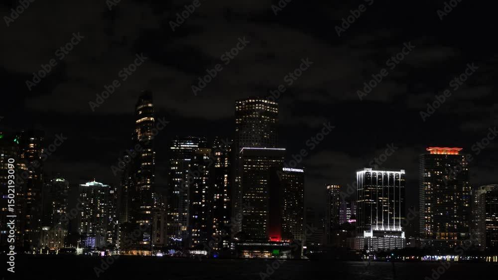 An impressive view of downtown Miami at night with illuminated buildings and city reflections sparkling over the water An impressive view of downtown Miami at night with illuminated buildings and city reflections sparkling over the water
