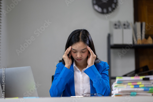 Businesswoman working with paperwork in office, she is seriously working, is stressed and tired. Asian woman who is suffering from headache and stress due to overwork.