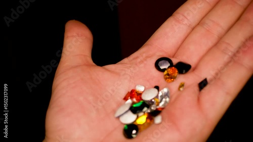 gemstones on a white table in multicolor illumination, A man's hand holds the jewels