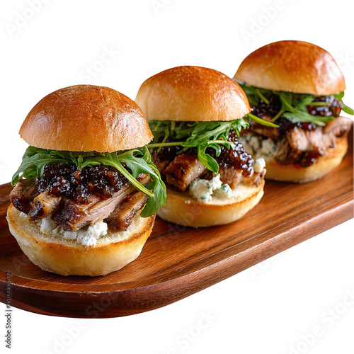 Three gourmet sliders with meat arugula and sauce on a wooden board against a black background