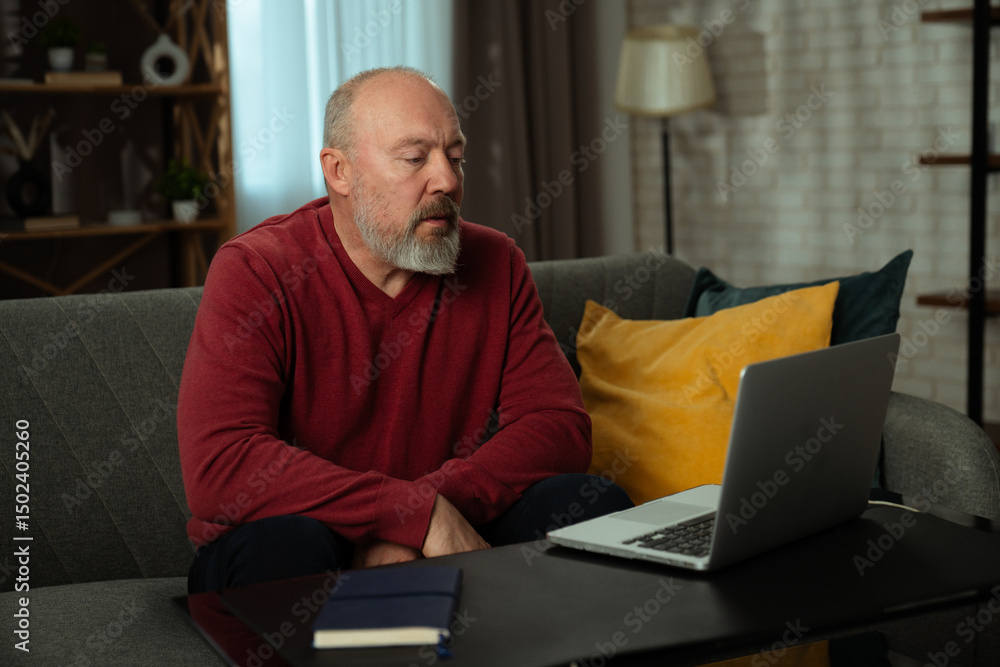 Senior Man Using Laptop at Home on Couch Senior Man Using Laptop at Home on Couch