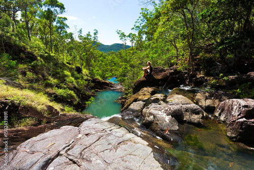Bushwalker overlooking a tropical creek view with surrounding green forest at Attie Creek Waterfall in Queensland, Australia