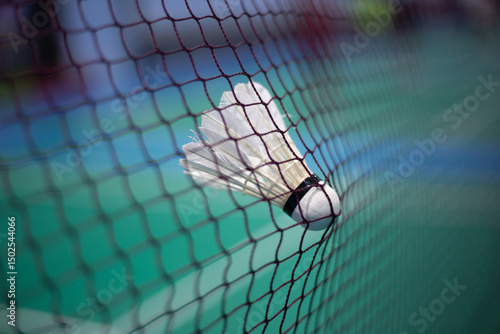 A badminton shuttlecock flies in mid-air on the playing field.