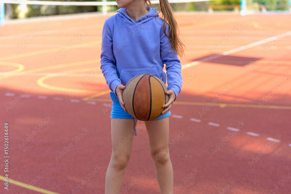 Naklejka premium Teenage girl playing basketball on the playground. Children and sports.