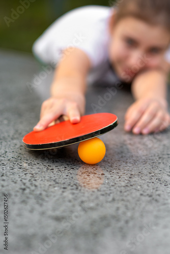 Table tennis, yellow ball and rackets close up in the hands of a girl, outdoor sport leisure activity. Children and sports.