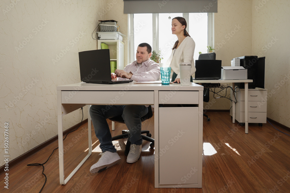 Young professionals managing paperwork and digital tasks side by side in a compact but organized home office, where teamwork and natural light enhance focus and productivity Young professionals managing paperwork and digital tasks side by side in a compact but organized home office, where teamwork and natural light enhance focus and productivity