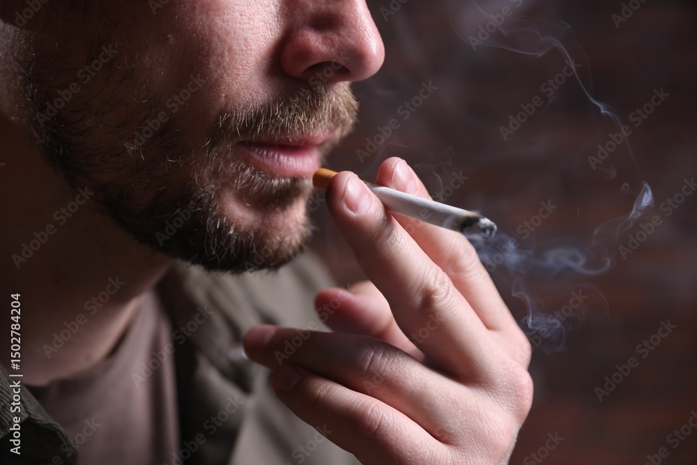 Fototapeta premium Man smoking cigarette on blurred background, closeup