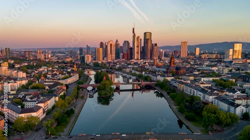 Aerial sunrise hyper time lapse view of the skyline of Frankfurt, Germany, and River Main with golden sunlight