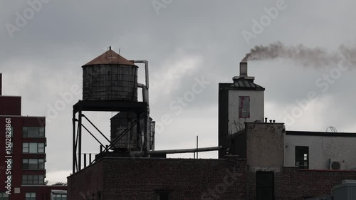 New York, New York, USA A residential house, a rooftop water tank, and a smokestack with smoke.  