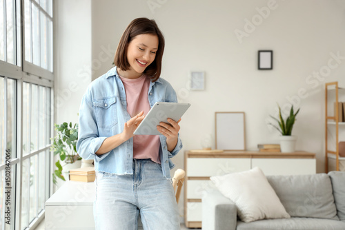 Young woman using tablet computer near window at home