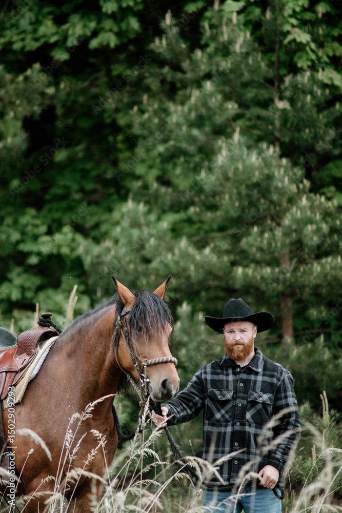 Fototapeta premium cowboy man with red beard in hat with horse close-up, friendship with animal