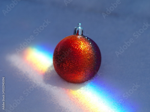 Red and gold ornament is sitting on top of a snow covered surface