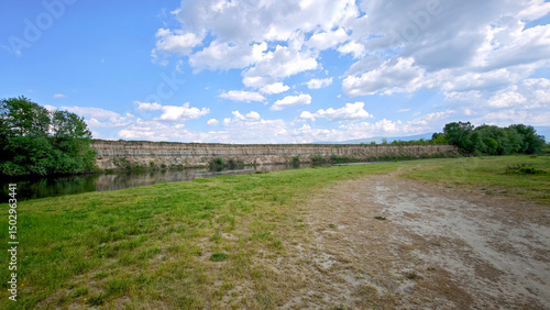 Panoramic view of an eroded riverbank along the Maritsa River in Bulgaria, with cloudy skies and exposed soil by the water.