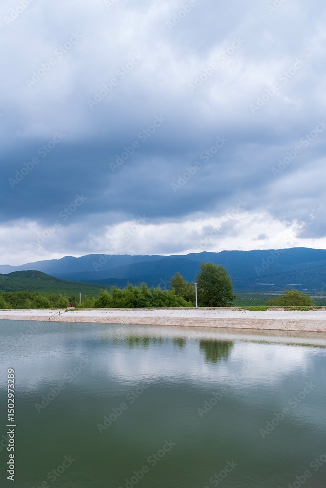 Obraz premium Lake under Ominous Clouds with Mountain Backdrop