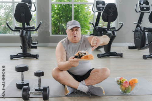 Fat young man makes hand gesture not wanting to eat those bad things in the gym