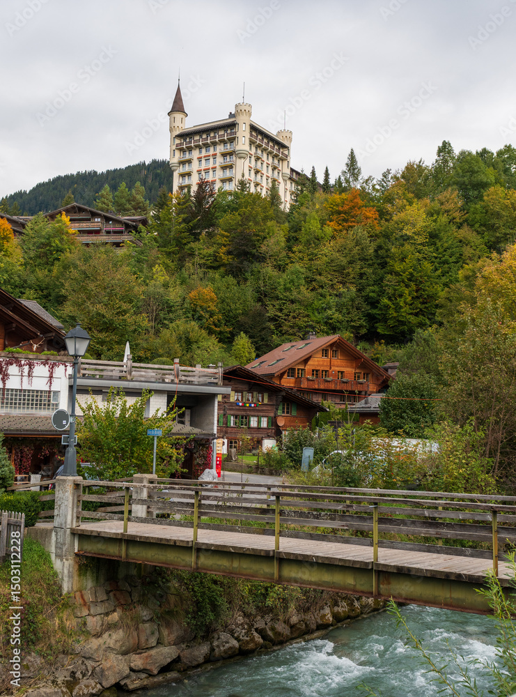 Fototapeta premium Capture the tranquil beauty of Lake Lauenen in the Bernese Oberland during autumn. The lake's emerald waters mirror the vibrant hues of surrounding forests, where golden larches and fiery maples