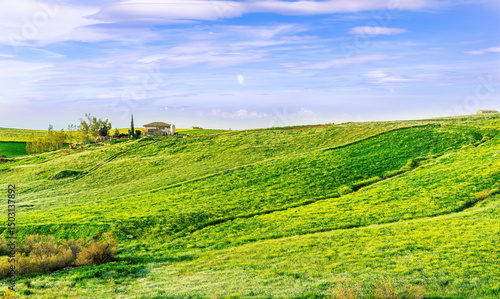 amazing greeen hills and fields in a spring or summer rustic landscape with rustic village on agricultural hills with beautiful colorful sky and mountains