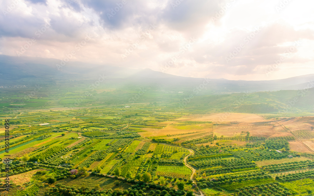 Obraz premium sunset valley landscape with green trees and gardens among beautiful mountains with colorful cloudy sky on background