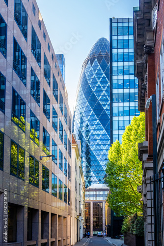 Photography View of the Gherkin skyscraper framed by narrow street buildings in the City of