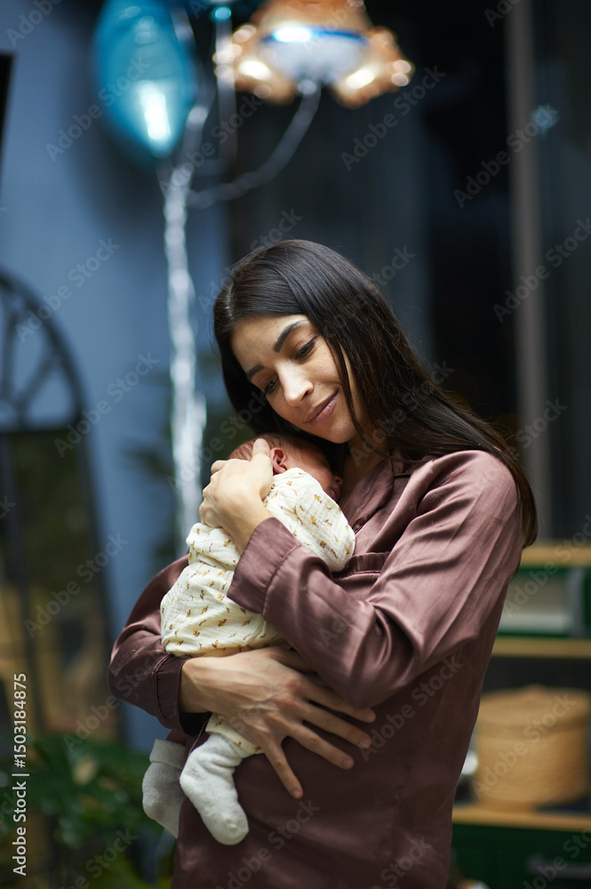 Fototapeta premium Young mom holding in her hands infant boy at home
