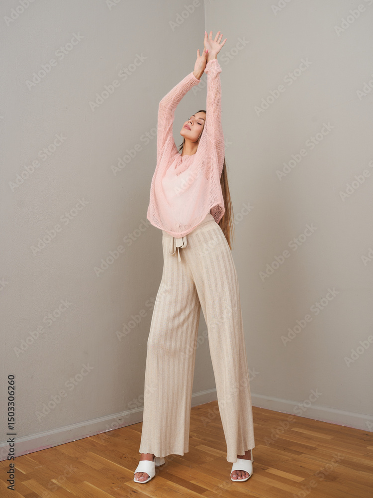 Fototapeta premium Young woman poses in stylish clothing in bright indoor setting