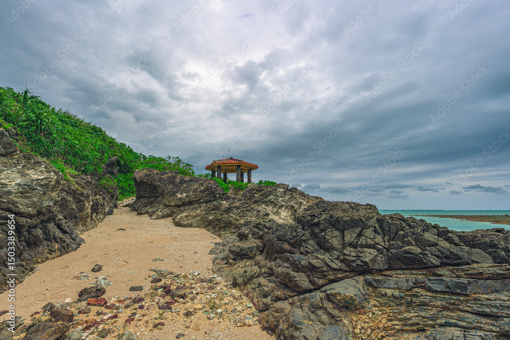 Fototapeta premium 観音ビーチの岩と緑に囲まれた東屋の風景 梅雨の石垣島