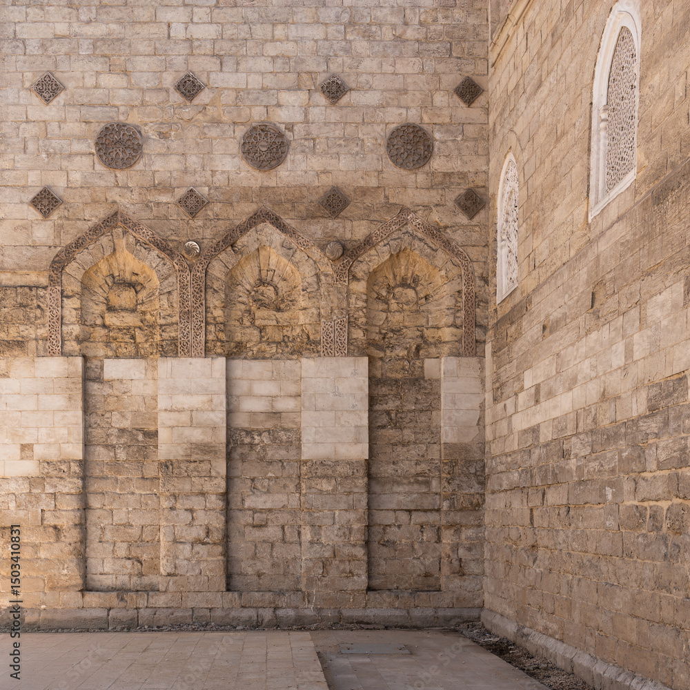 Fototapeta premium The Mosque of al-Zahir Baybars stands majestic in Cairo, Egypt, showcasing intricate stonework and architectural details under soft golden hour light