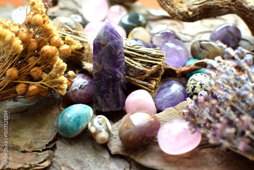 Beautiful natural stones, amethyst obelisk and dry herbs on wooden background. Healing crystals. Predictions and magic.