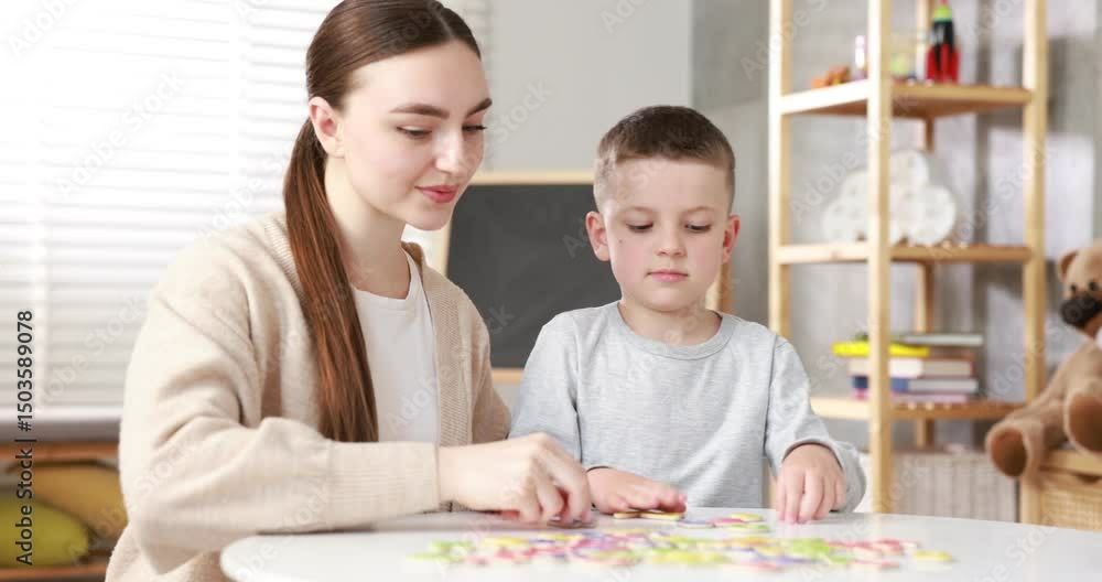 Dyslexia. Mother and her son learning letters at table indoors Dyslexia. Mother and her son learning letters at table indoors