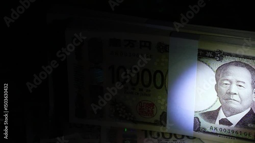 暗闇でライトで照らす札束