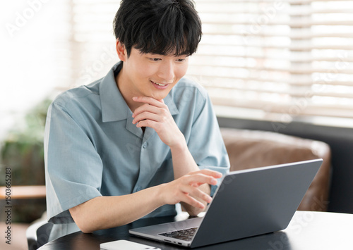 若い日本人男性がノートパソコンを開き作業をしている。