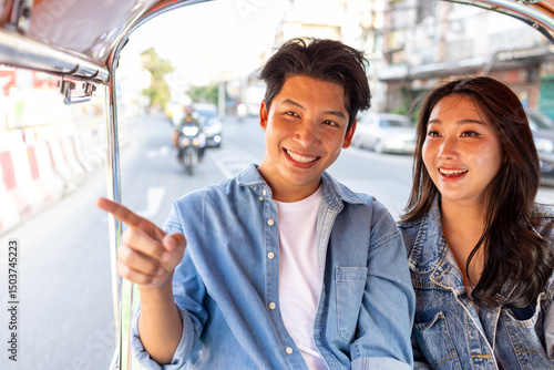 Photography Young Asian couple tourist traveling on local Tuk Tuk Taxi exploring the city in