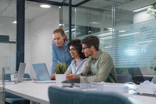 Multiethnic business team discussing new project working on laptop in modern office