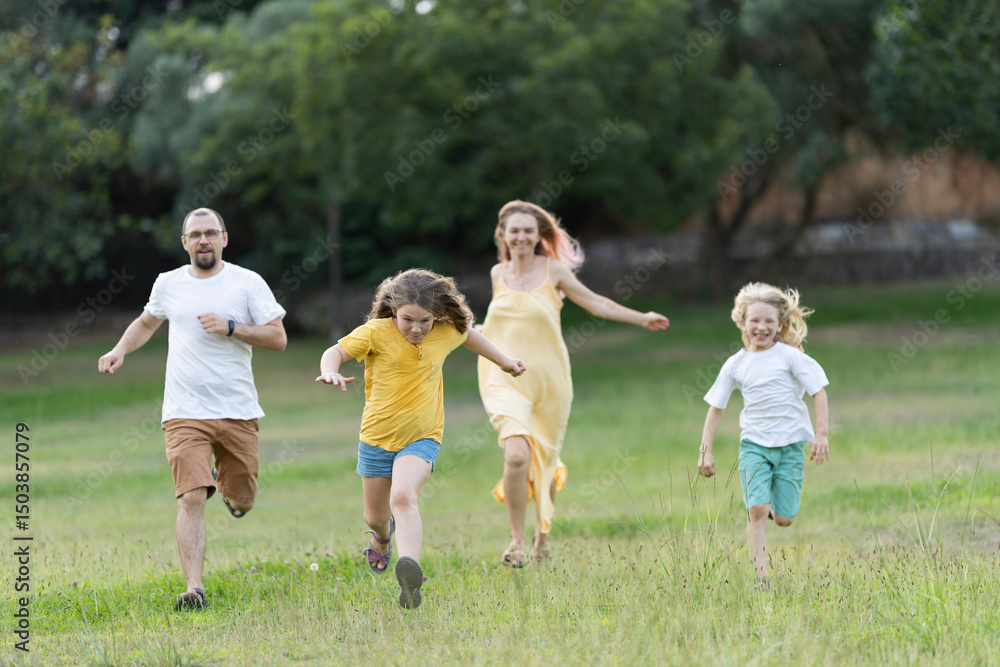 Fototapeta premium Happy family running and playing together in a park