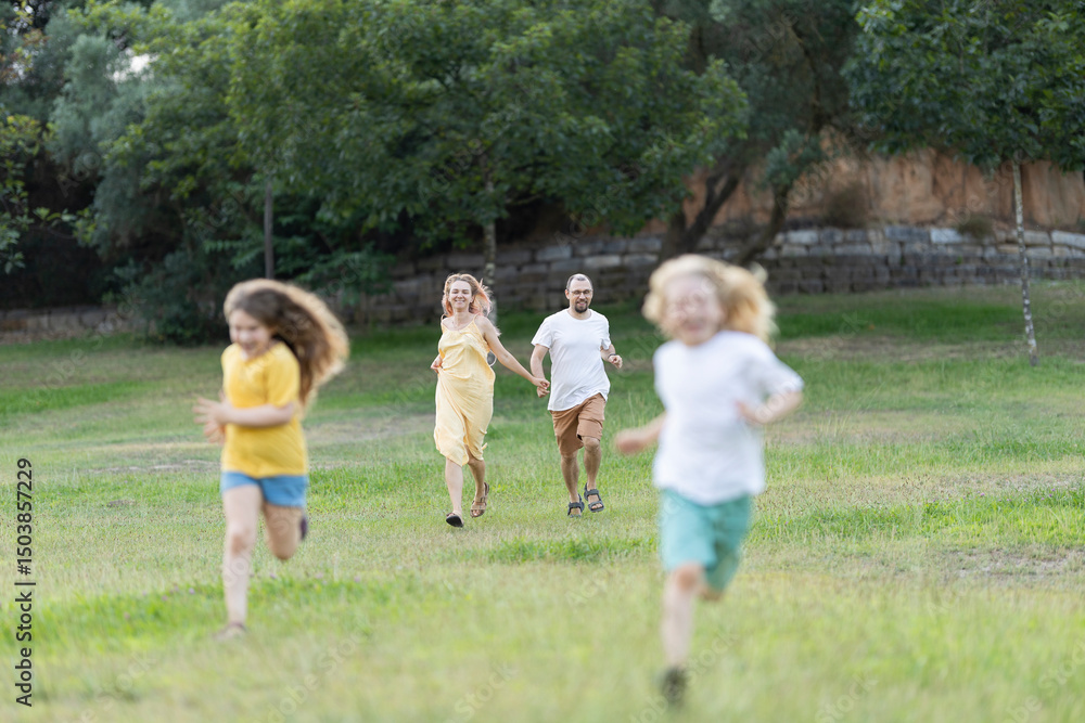 Happy family running and playing together in park Happy family running and playing together in park