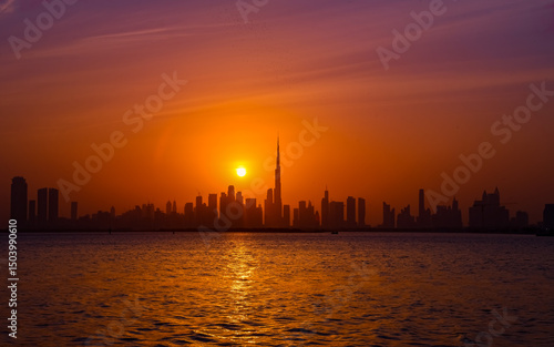 Beautiful sunset view of the Dubai skyline with Burj Khalifa silhouette, captured from the Dubai Creek Harbour Waterfront. A striking urban landscape perfect for travel, editorial, or commercial use.