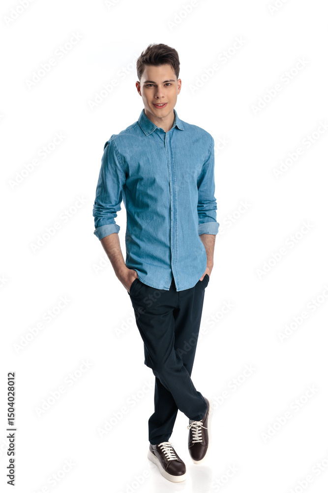 Fototapeta premium confident young guy in blue denim shirt holding hands in pockets and smiling
