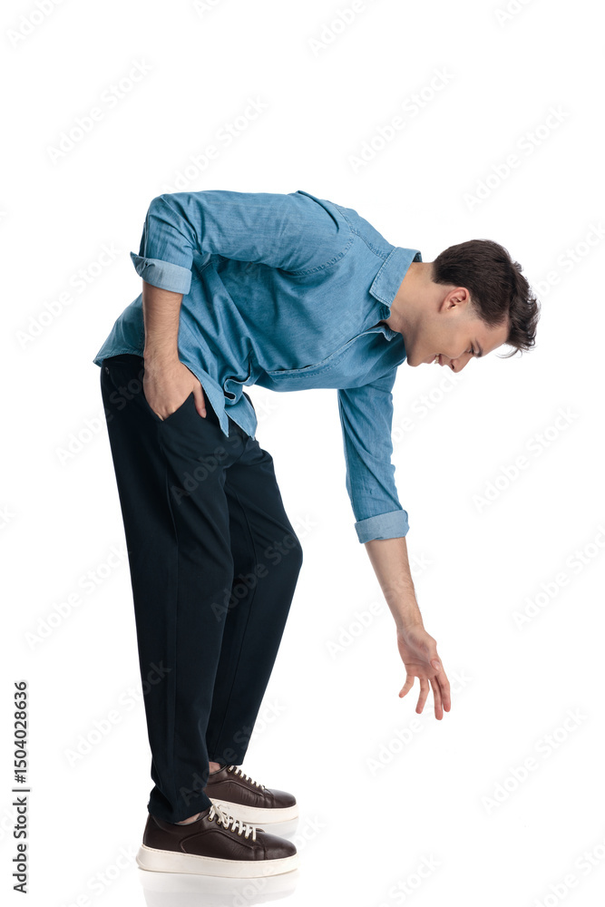 side view of happy casual guy bending over and picking up something from floor side view of happy casual guy bending over and picking up something from floor