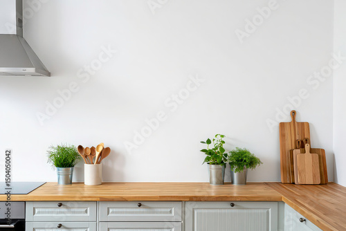 Bright kitchen design with light gray cabinets, wooden countertop. Green plants, wood spoons, cutting boards. Modern interior design. Scandinavian style. Nobody. Cozy cooking space, home decor